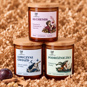 Piramida świec: Alchemik u góry, Łowczyni Gwiazd i Podróżniczka u dołu, na papierowym wypełniaczu. Podpis: Alchemik w kolekcji z postaciami Łowczyni Gwiazd i Podróżniczka. Wizualizacja aranżacji, nie zestaw sprzedażowy.